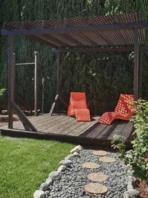 brown pergola with red chairs and stone pathway