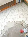 white hexagon tile being laid onto bathroom floor