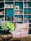 green and white bookcase behind pink armchair