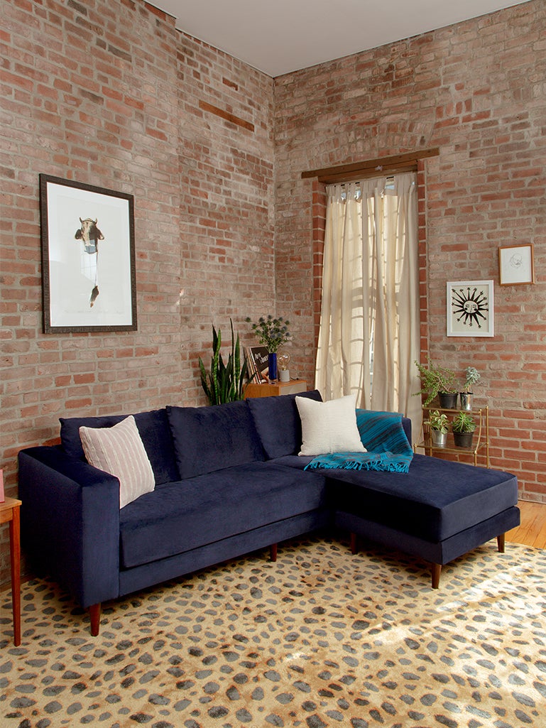 blue sofa in front of a brick wall