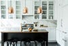 white kitchen with copper pendant lights over black island