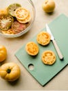 mint green cutting board with yellow tomatoes on top