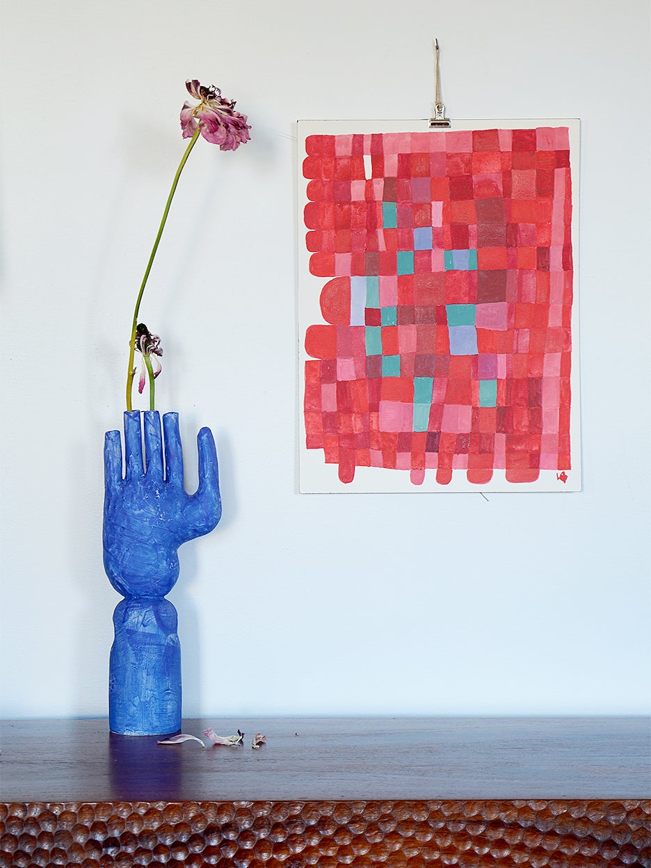 red painting hanging above a blue hand sculpture