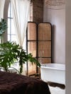 white clawfoot bathtub in front of cane room divider