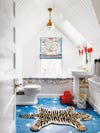white kids bathroom with blue star floor tile and red sconces