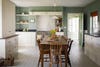 green kitchen with white cabinets and rustic dining table