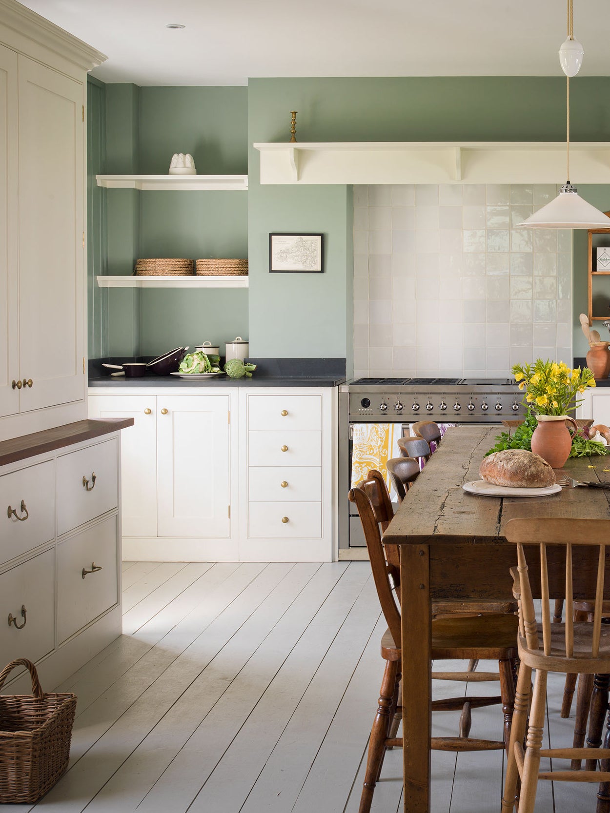 green kitchen with white cabinets and rustic dining table