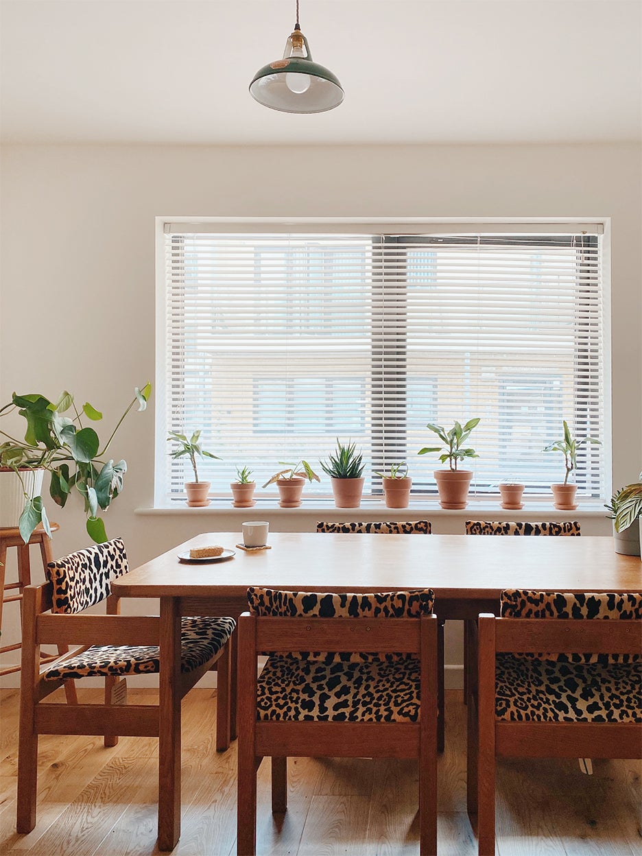 dining room table with windowsill of herbs and leopard print chairs