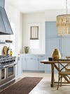 light blue kitchen with wooden table and woven pendant