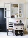 white room with glass front cabinet and black door