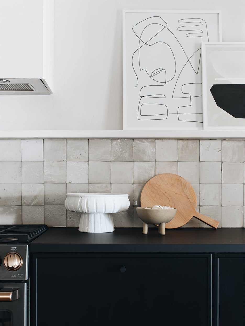black kitchen cabinets white zellige tile backsplash art on ledge