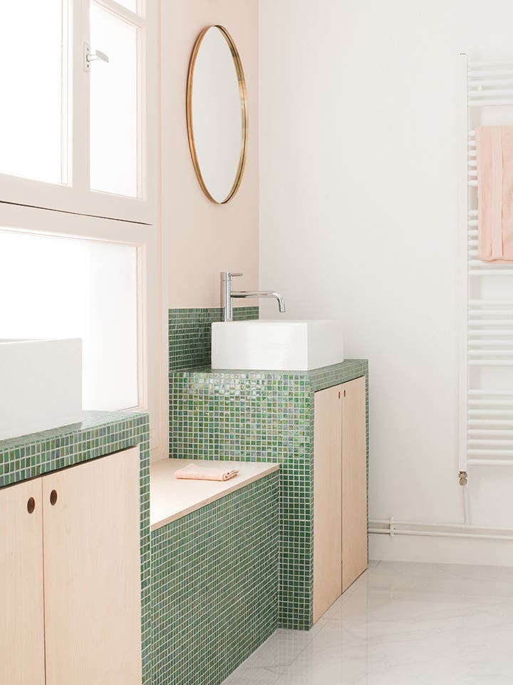 pink bathroom with small green tiles around the sink