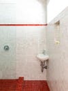 white zellige tile shower nook with strip of red tiles