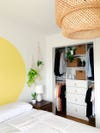 bedroom with yellow mural and open closet
