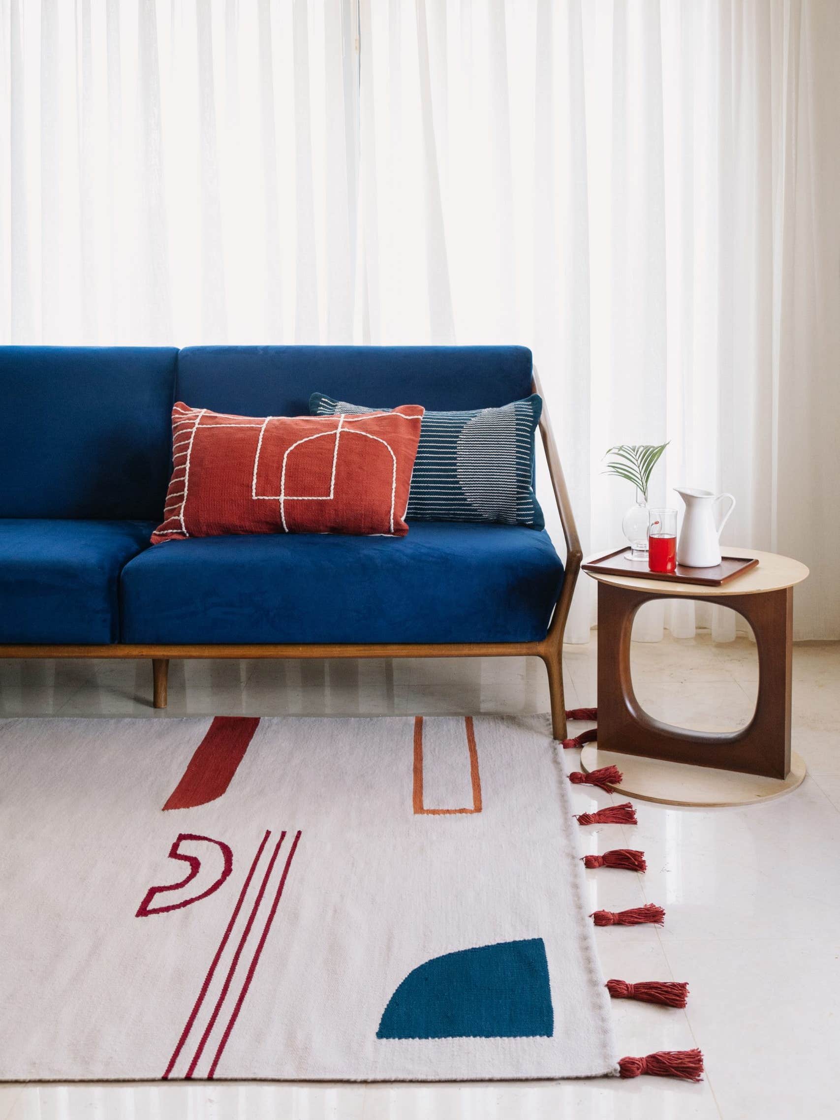 blue sofa in living room with multicolored rug
