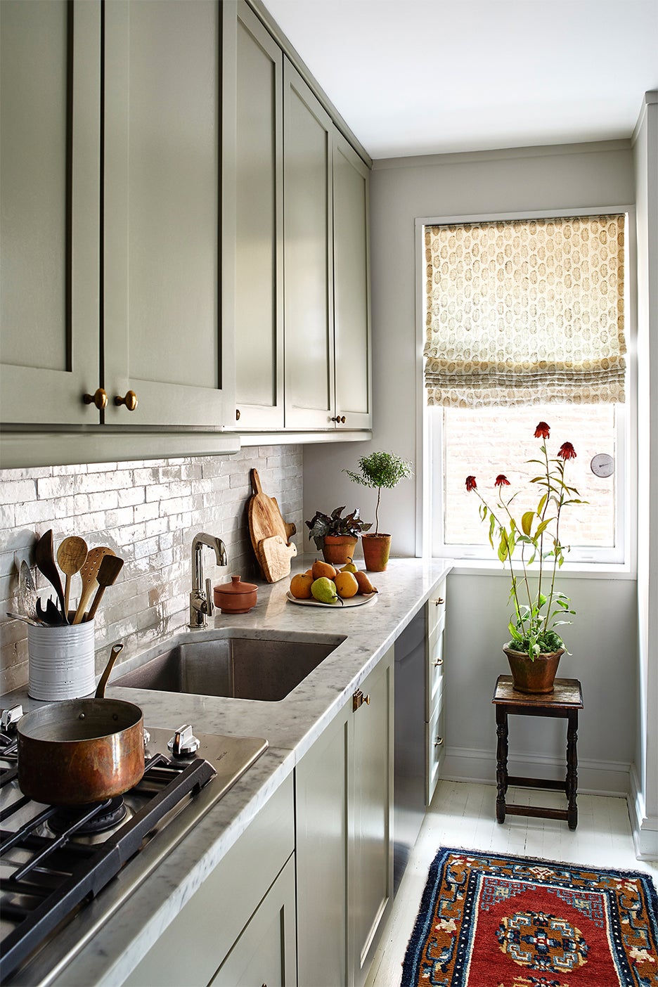 grey-green galley kitchen with white tile backsplash