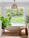 bathroom with huge window overlooking backyard, terracotta tiles, and white tub