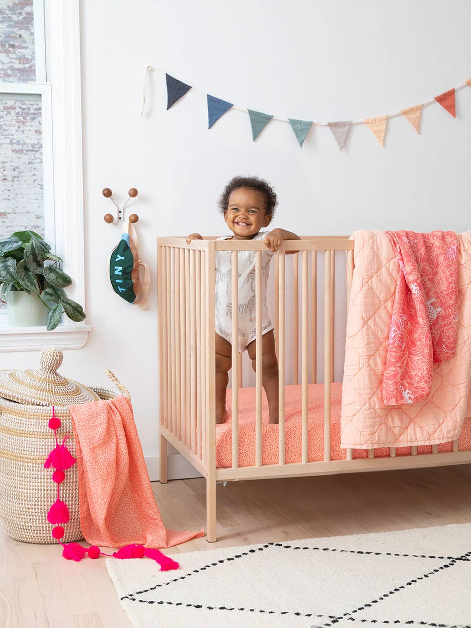 baby in crib with pink bedding