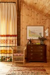 Woven chair and antique dresser in wood-paneled room