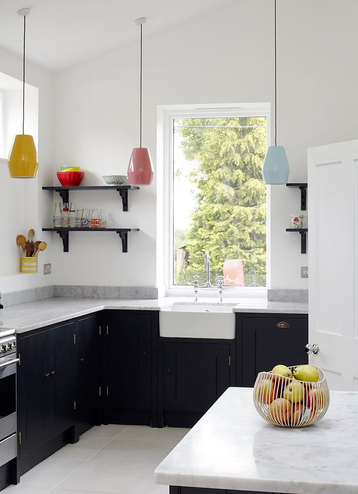 white kitchen with black cabinets and multicolored pendants