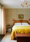 Bedroom with yellow bedspread and floral wallpaper