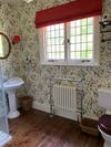 Wallpapered bathroom with red window shade