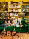 Two men sitting on green velvet couch with their baby.