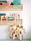Rattan kids' book shelf with dress hanging from hook.