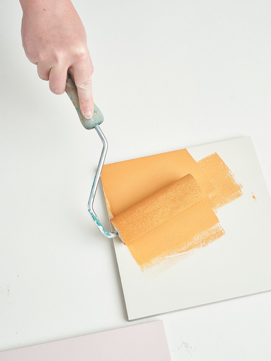 person rolling paint on tile