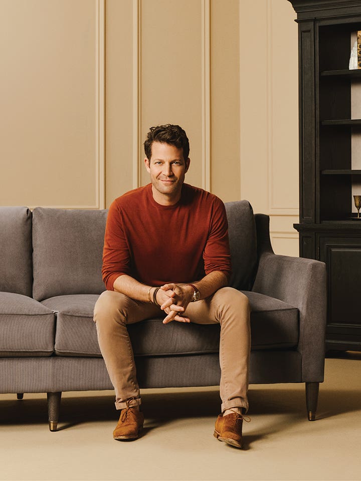 Nate Berkus sitting on a sofa wearing a maroon sweater