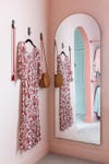 pink room with dress on a hook and arched mirror