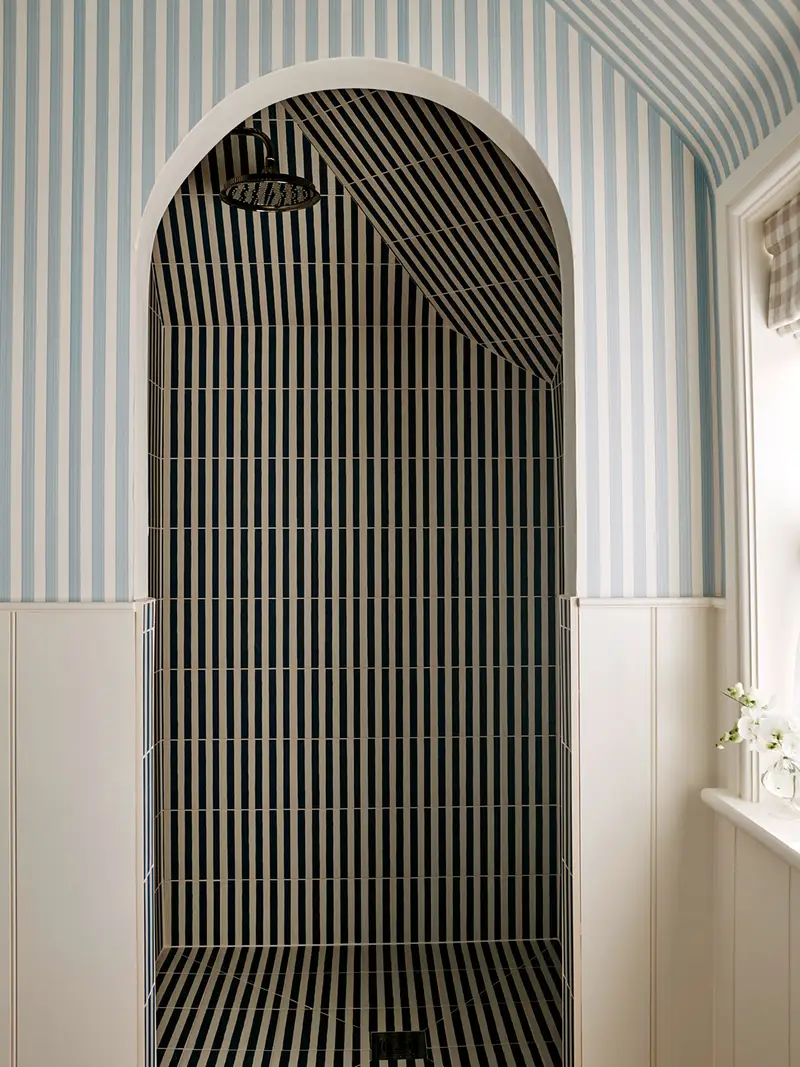 Bathroom with black-and-white striped tile and blue-and-white striped wallpaper.
