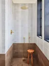 White-tiled bathroom with brown tile along the floor and bottom half of shower.