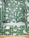 Green and white geometric tile covering shower walls and tab face.