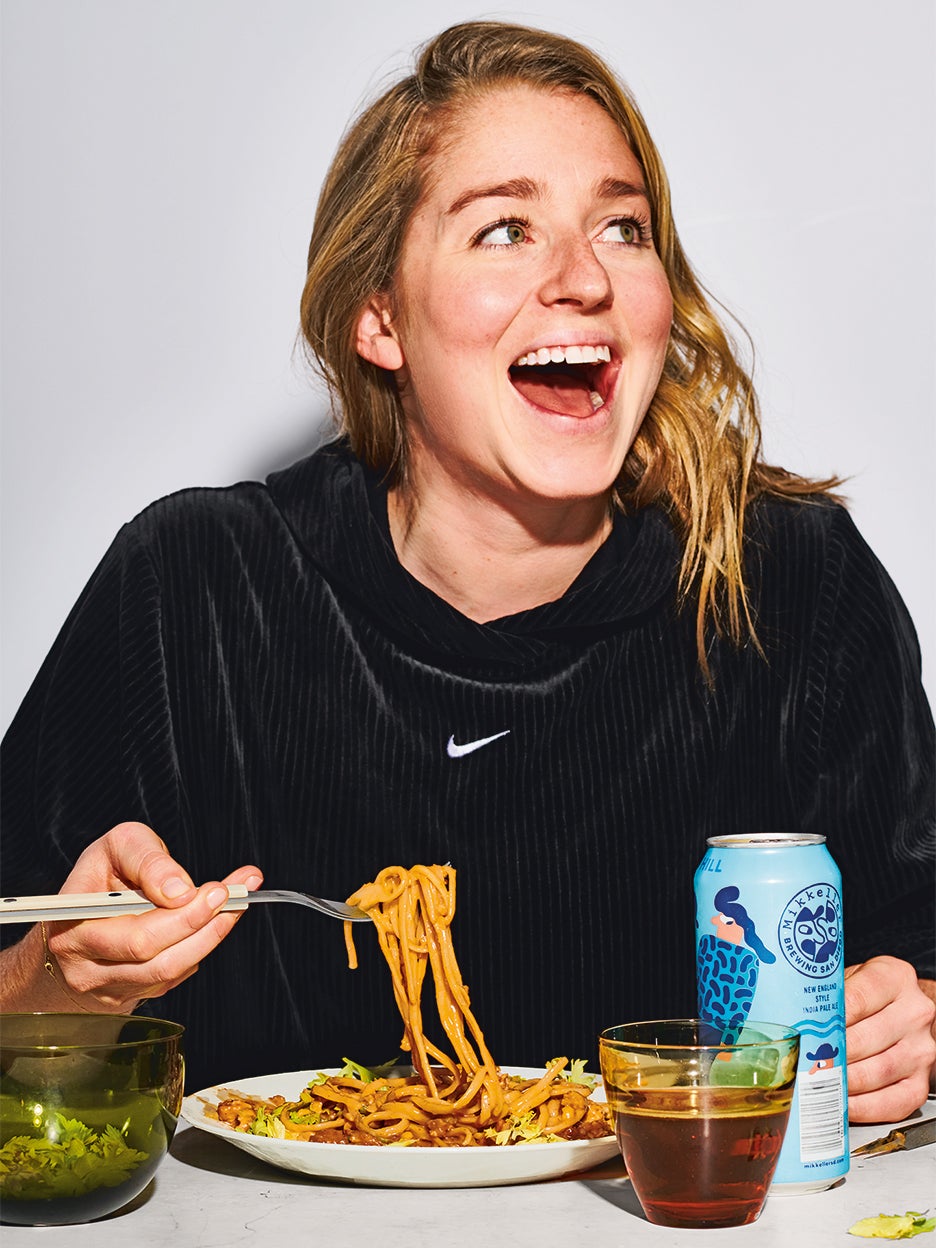 Molly Baz in a black sweatshirt eating pasta