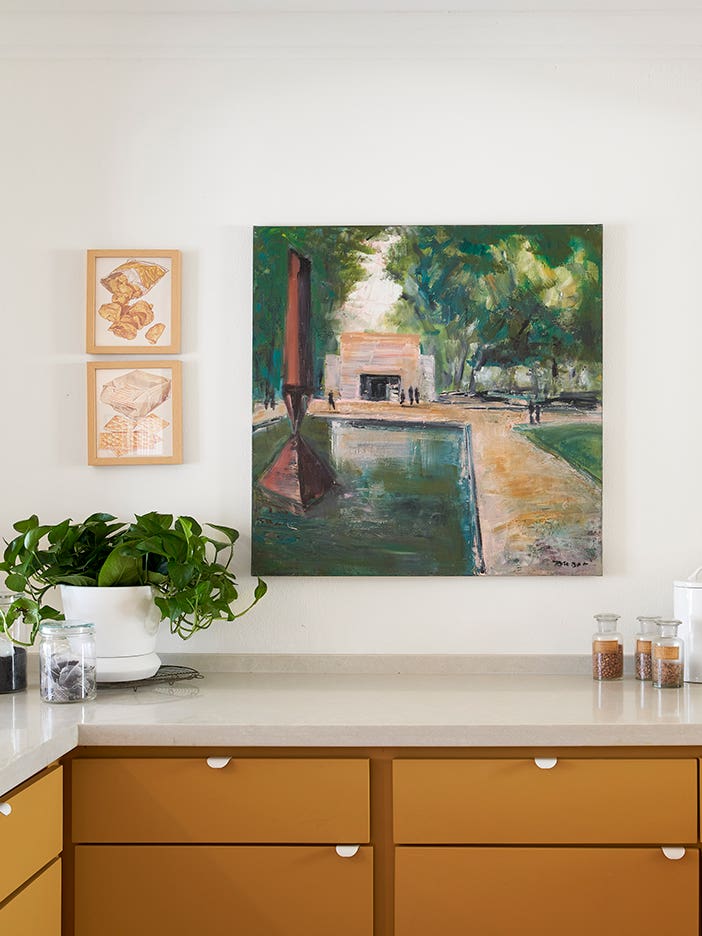 landscape painting above orange kitchen cabinets
