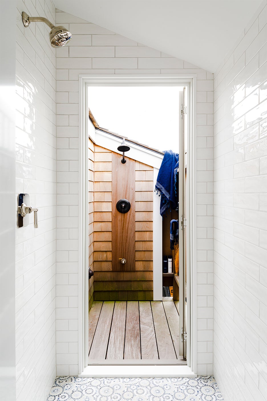 indoor tiled shower leading to wood outdoor shower on balcony
