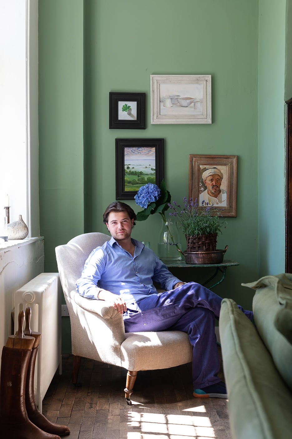 man sitting in cream armchair in green room