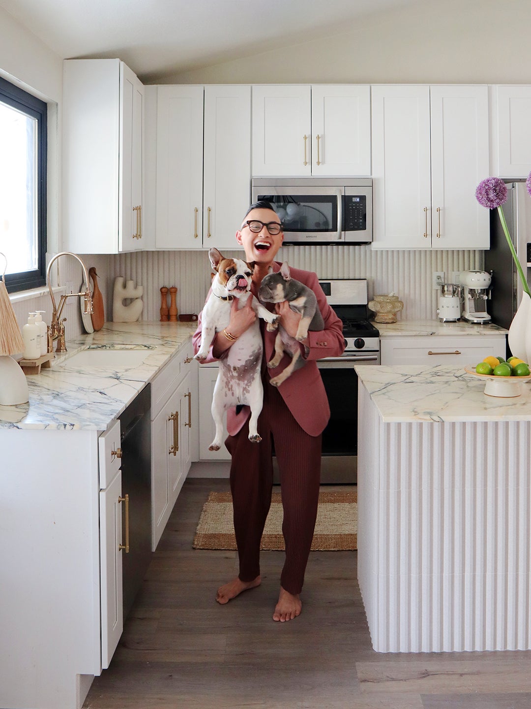 man with two french bulldogs in kitchen