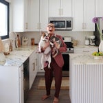 man with two french bulldogs in kitchen