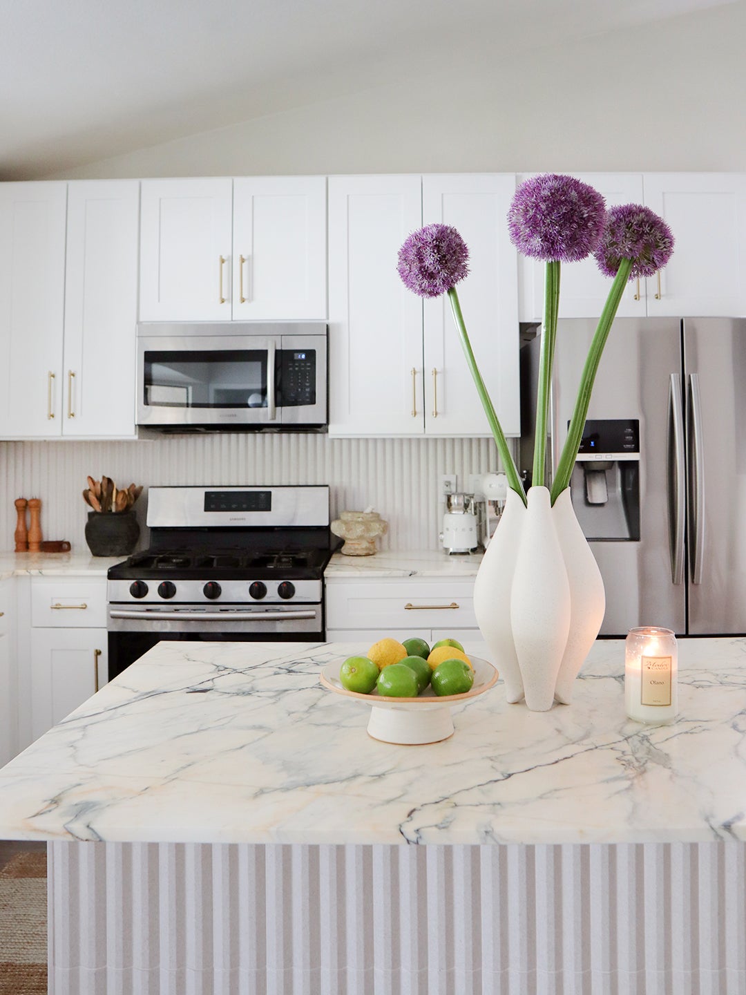 layered white kitchen with purple floral arrangement