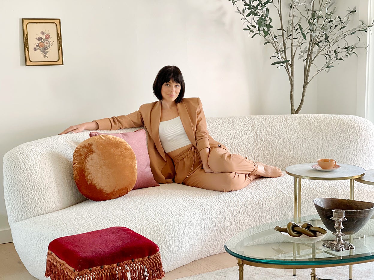 Woman on white sofa in a tan suit