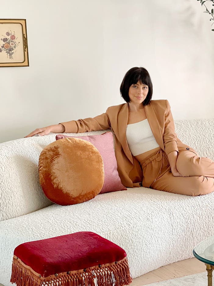 Woman on white sofa in a tan suit