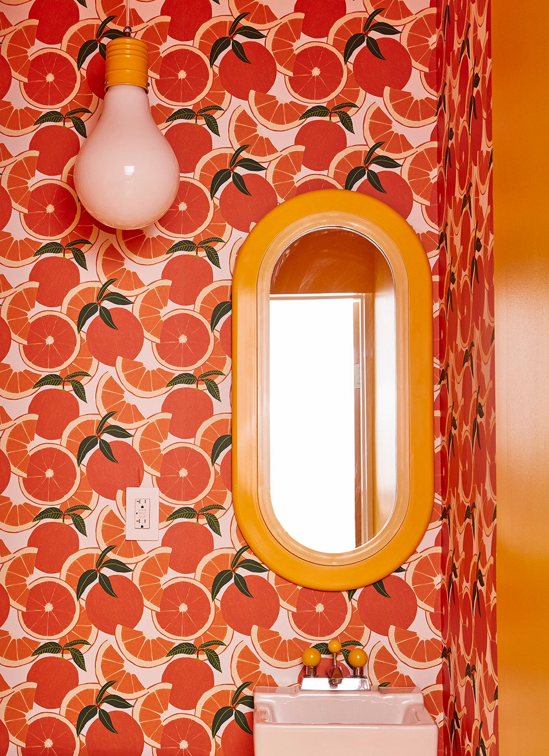 Orange citrus wallpaper and yellow mirror in bathroom
