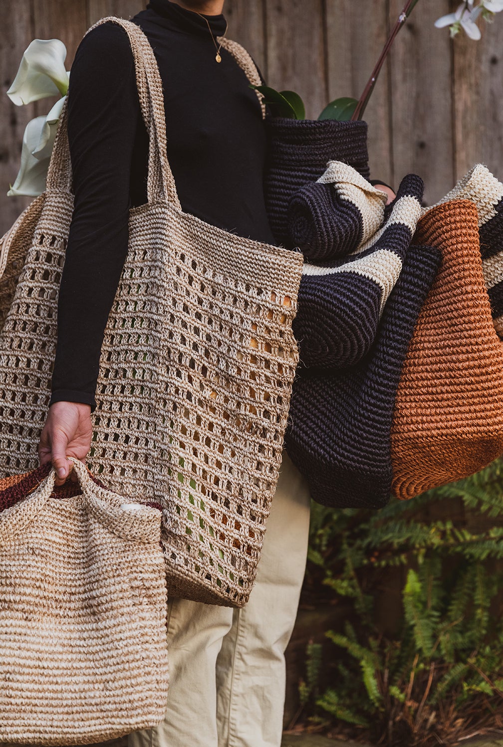Woman holding woven baskets and bags
