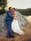 couple leaning against rock at their wedding