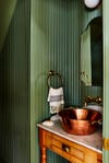 green paneled powder room with brass sink