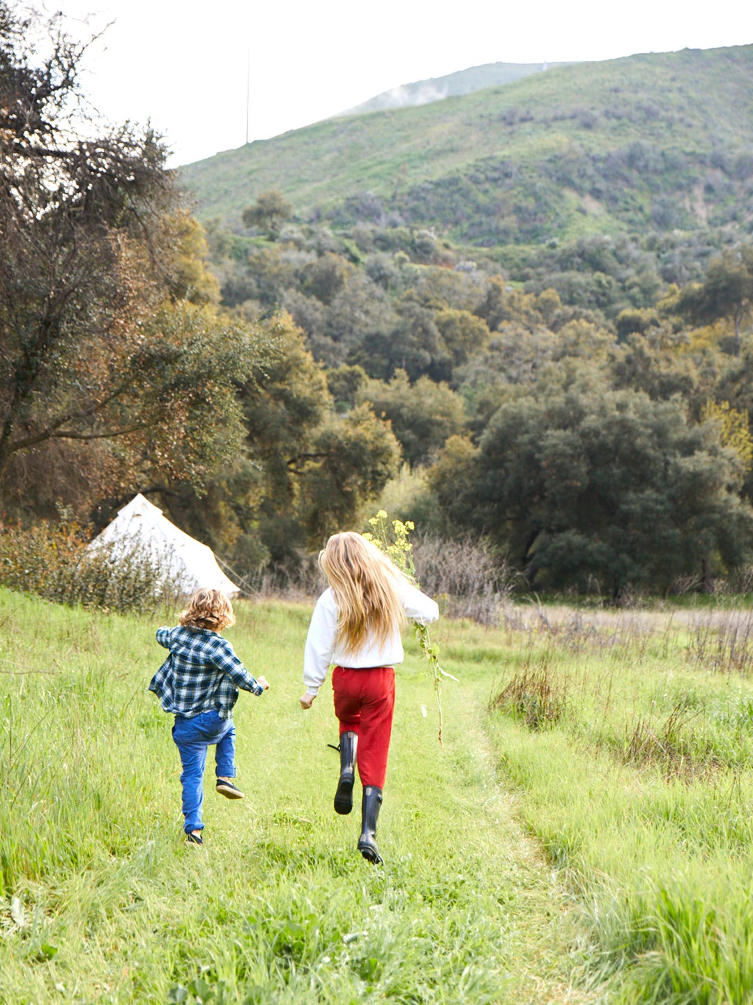 Two kids skipping in a field.