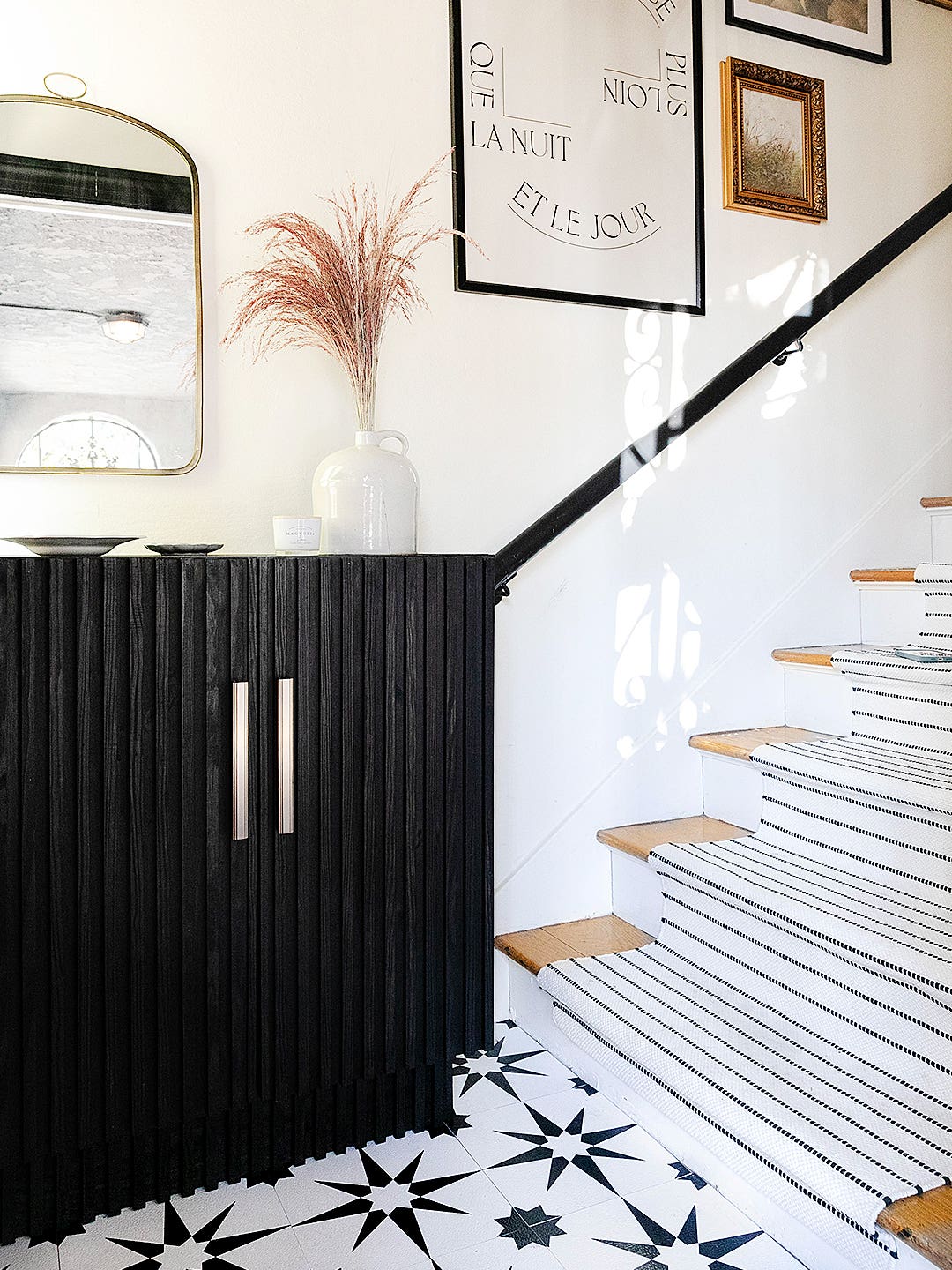 Entryway, Dowel IKEA cabinet, painted black, stair runner, and gallery wall