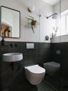 toilet mounted into black tile wall